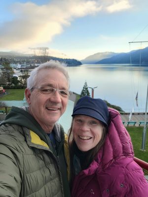 Jim Rivard, Port Alberni Electrician, poses with his wife Michelle. Both smile at the camera with the Port harbour in the background.